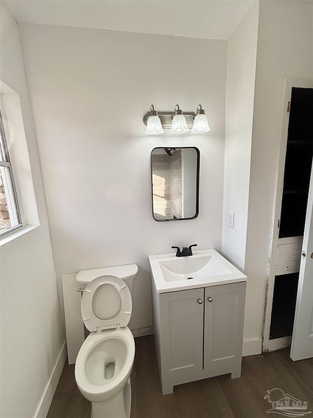 bathroom featuring vanity, toilet, wood finished floors, and baseboards