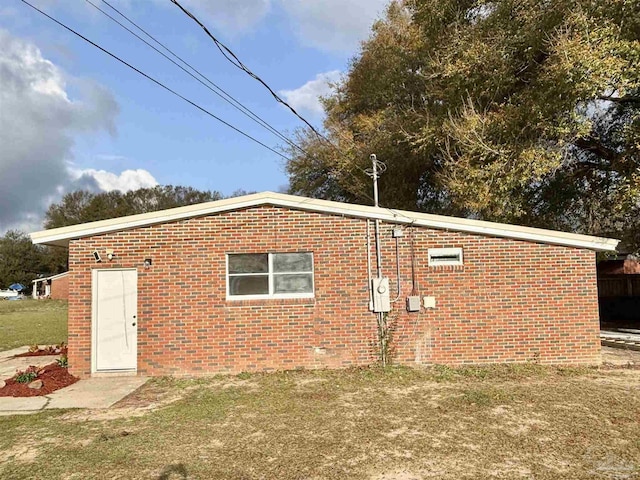 view of property exterior featuring brick siding and a lawn