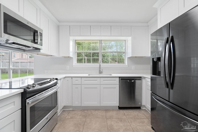 kitchen featuring appliances with stainless steel finishes, white cabinetry, sink, and light tile patterned floors