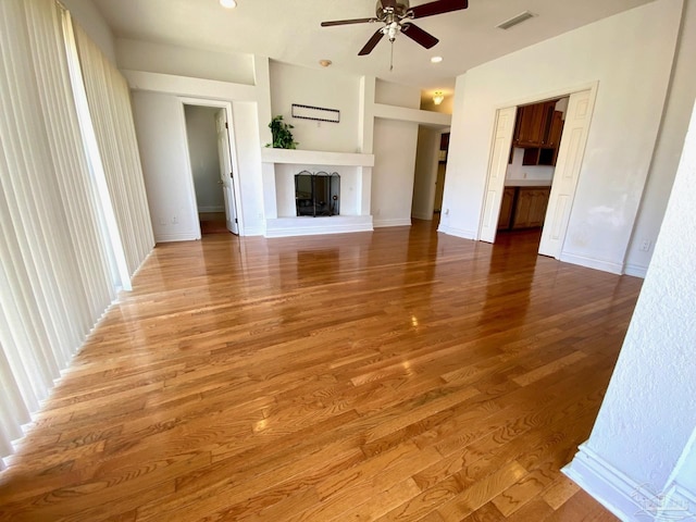 7208 Bayshore Dr, Milton, FL 32583 - unfurnished living room with a ceiling fan, a fireplace with raised hearth, wood finished floors, recessed lighting, and baseboards
