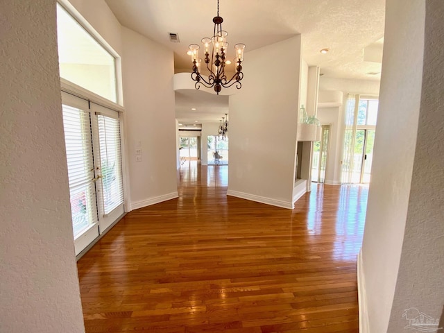 7208 Bayshore Dr, Milton, FL 32583 - corridor featuring a chandelier, a textured wall, plenty of natural light, and wood finished floors
