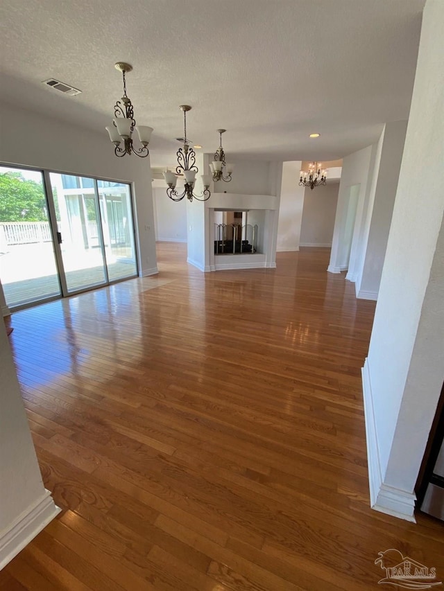 7208 Bayshore Dr, Milton, FL 32583 - unfurnished living room with a chandelier, wood finished floors, baseboards, and a textured ceiling