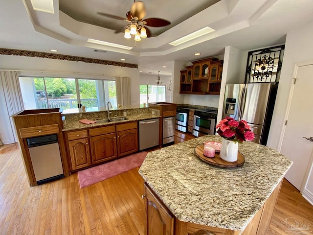 7208 Bayshore Dr, Milton, FL 32583 - kitchen featuring stainless steel appliances, a large island with sink, a sink, a tray ceiling, and light wood-style floors