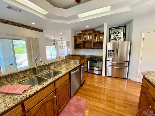 7208 Bayshore Dr, Milton, FL 32583 - kitchen with appliances with stainless steel finishes, light wood-style flooring, a sink, a skylight, and brown cabinetry