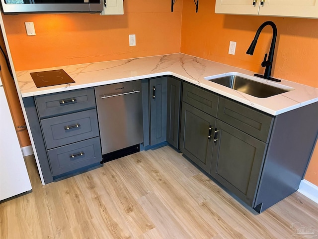 kitchen featuring stainless steel dishwasher, sink, light wood-type flooring, and light stone countertops