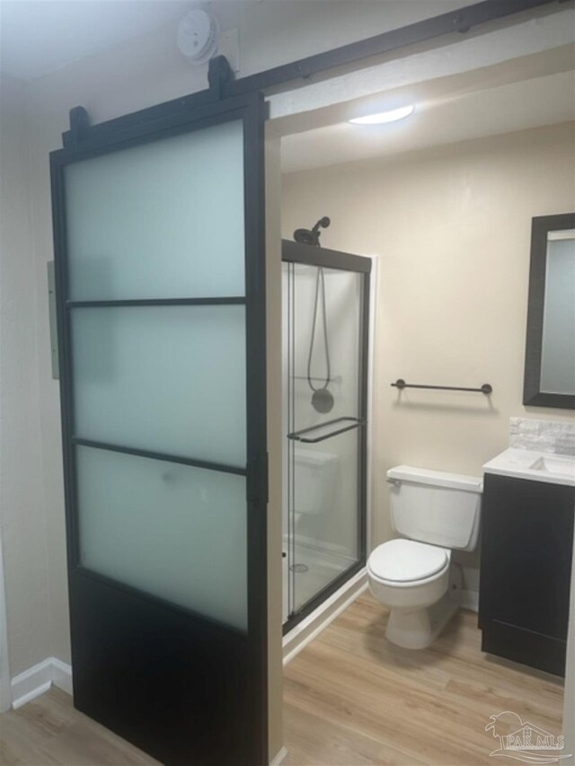 bathroom with vanity, a shower with door, wood-type flooring, and toilet