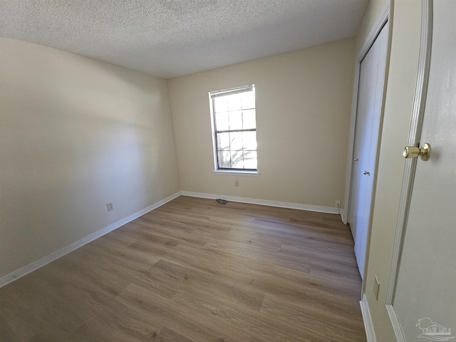 unfurnished bedroom with a closet, light hardwood / wood-style floors, and a textured ceiling