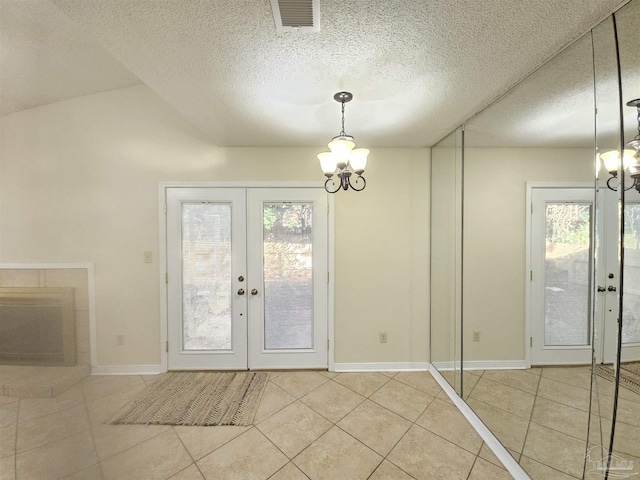 foyer featuring a notable chandelier, plenty of natural light, tile patterned floors, and french doors