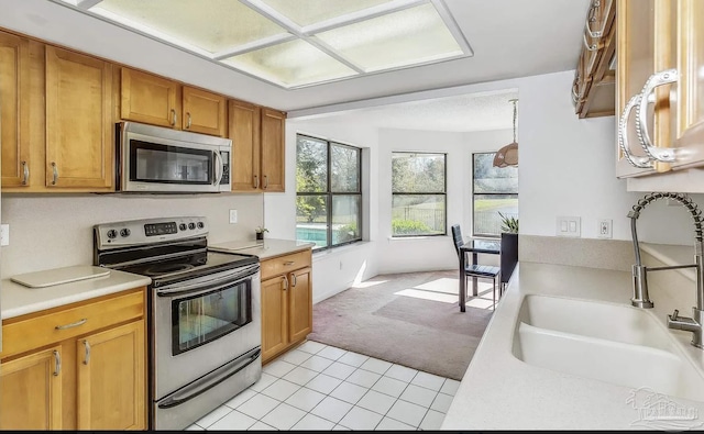 kitchen with appliances with stainless steel finishes, light colored carpet, and sink