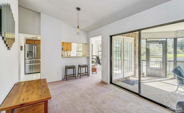 doorway to outside with a textured ceiling, light carpet, and lofted ceiling