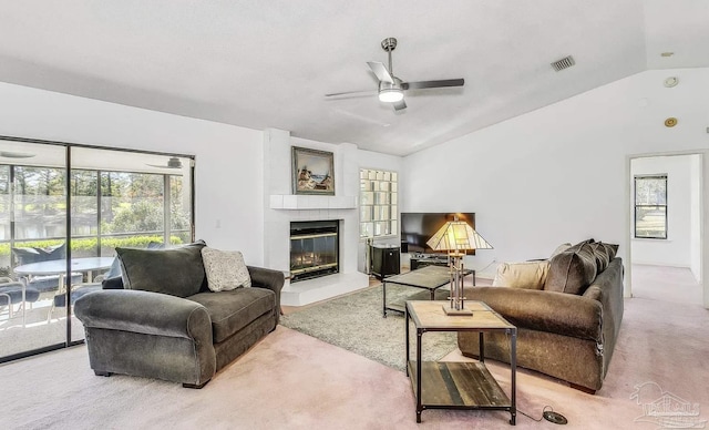 carpeted living room with ceiling fan, a large fireplace, and lofted ceiling