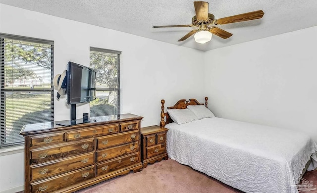 carpeted bedroom with multiple windows, ceiling fan, and a textured ceiling