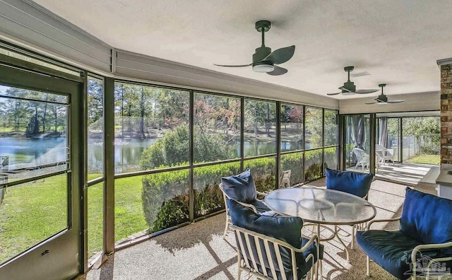 sunroom / solarium featuring ceiling fan and a water view