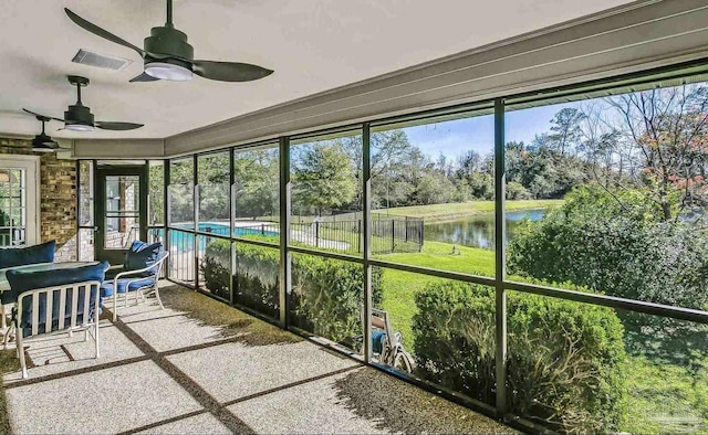 unfurnished sunroom with ceiling fan, a water view, and plenty of natural light