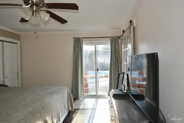 bedroom with ceiling fan, a barn door, and crown molding