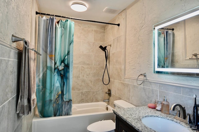 full bathroom with shower / bath combination with curtain, vanity, toilet, and tile walls