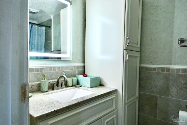 bathroom featuring vanity and tile walls