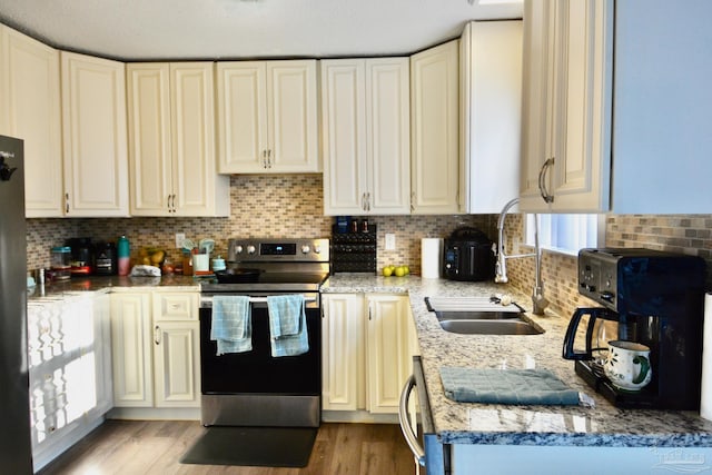 kitchen featuring backsplash, sink, stainless steel electric range, and light wood-type flooring