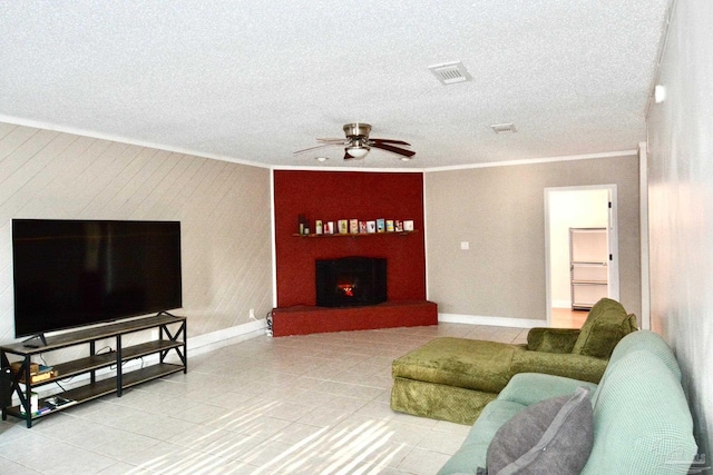 living room featuring tile patterned flooring, a textured ceiling, ceiling fan, and ornamental molding