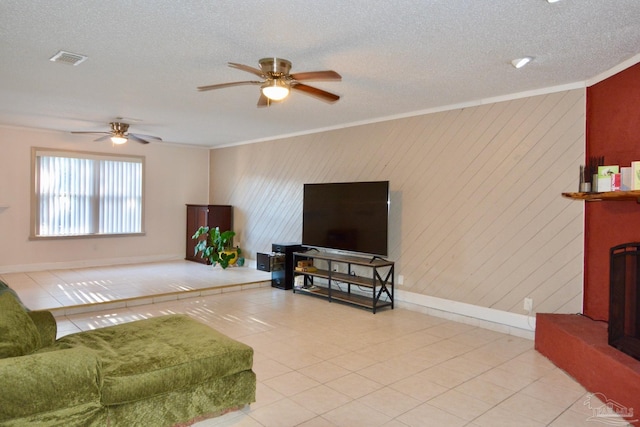 tiled living room with ceiling fan, a textured ceiling, and ornamental molding