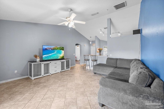 living room featuring a textured ceiling, vaulted ceiling, light tile patterned flooring, and ceiling fan