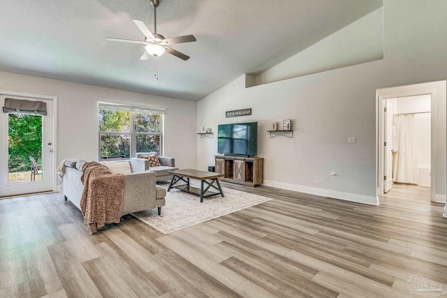 living room featuring light wood-type flooring, a textured ceiling, high vaulted ceiling, and ceiling fan