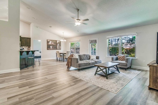 living room with light hardwood / wood-style floors, a textured ceiling, lofted ceiling, and a healthy amount of sunlight