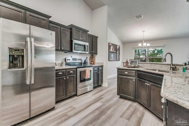 kitchen with dark brown cabinets, pendant lighting, vaulted ceiling, appliances with stainless steel finishes, and sink