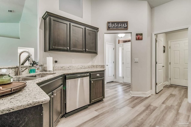 kitchen featuring light stone countertops, stainless steel dishwasher, sink, dark brown cabinets, and high vaulted ceiling