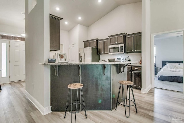 kitchen with kitchen peninsula, light hardwood / wood-style floors, a breakfast bar, and stainless steel appliances