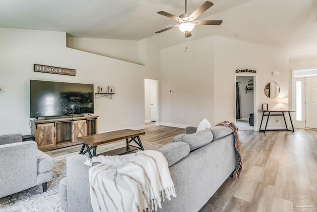 living room featuring ceiling fan, lofted ceiling, and light wood-type flooring