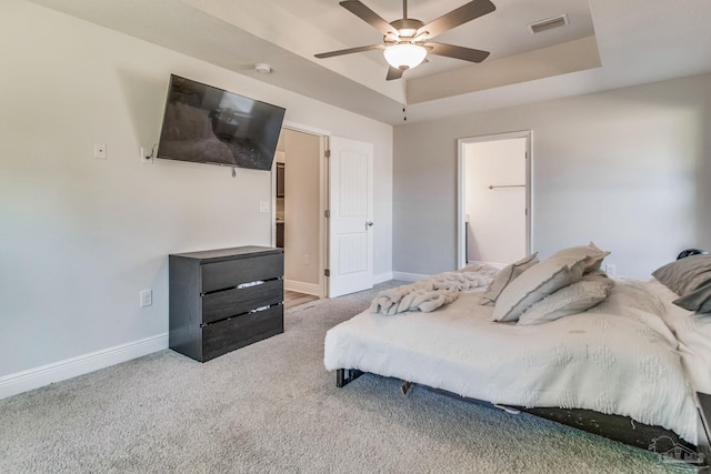 bedroom with light carpet, ceiling fan, and a raised ceiling