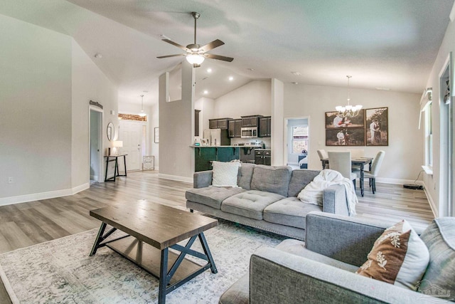 living room with ceiling fan with notable chandelier, high vaulted ceiling, and light hardwood / wood-style floors