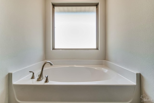 bathroom featuring plenty of natural light and a tub to relax in