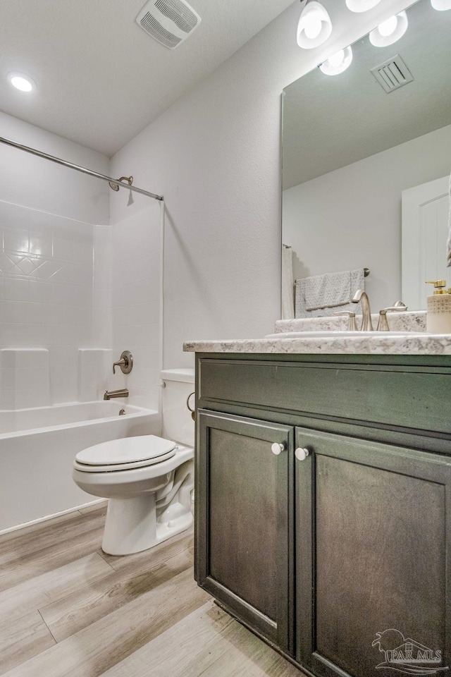 full bathroom with shower / washtub combination, hardwood / wood-style flooring, toilet, and vanity