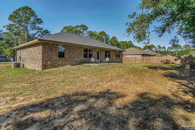 rear view of property featuring central AC unit, a yard, and a patio