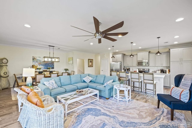 living room with ceiling fan, ornamental molding, light wood-type flooring, and recessed lighting