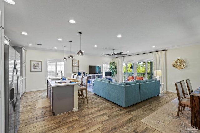 living area featuring light wood-style flooring, ornamental molding, baseboards, and recessed lighting