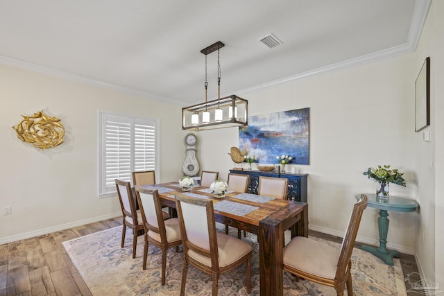 dining room featuring light wood-style floors, baseboards, visible vents, and ornamental molding