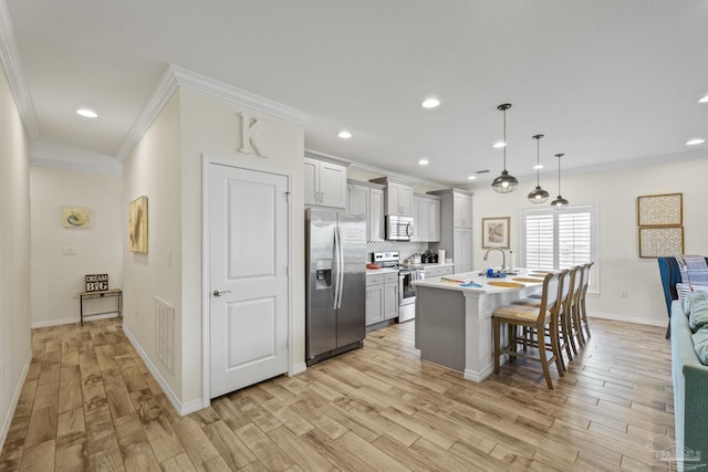 kitchen with stainless steel appliances, light countertops, light wood-style flooring, and a kitchen breakfast bar