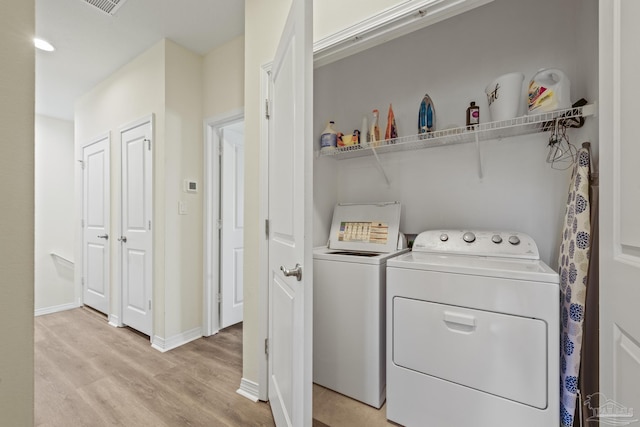 laundry area with laundry area, light wood finished floors, independent washer and dryer, and baseboards