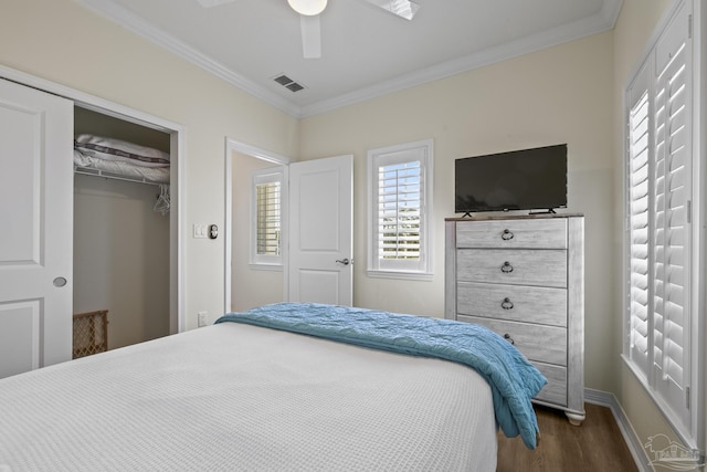 bedroom featuring visible vents, dark wood finished floors, ceiling fan, crown molding, and a closet