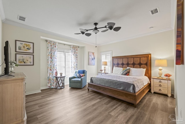 bedroom with visible vents, crown molding, and wood finished floors