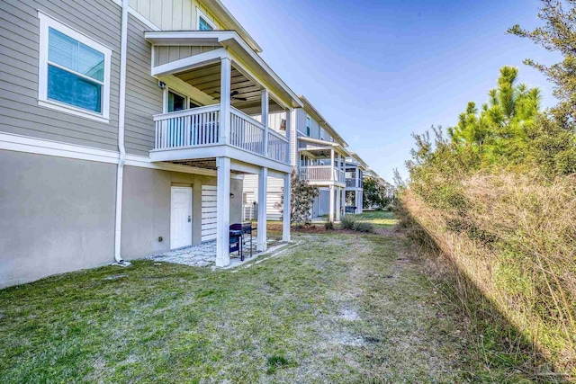 rear view of property featuring a patio area, board and batten siding, and a yard