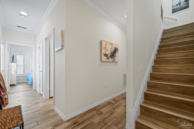 staircase featuring ornamental molding, wood finished floors, and baseboards