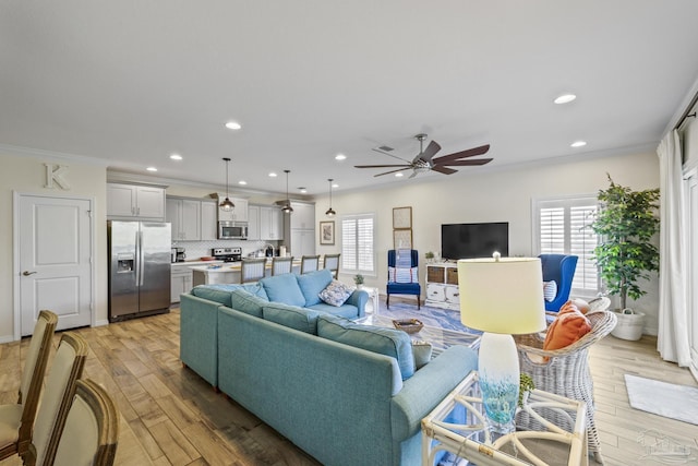 living room with a healthy amount of sunlight, light wood-style floors, crown molding, and recessed lighting