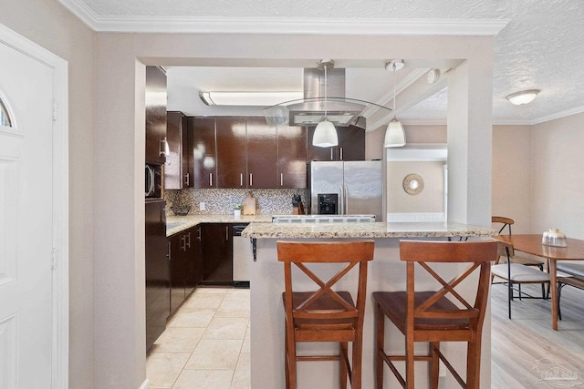 kitchen featuring crown molding, stainless steel appliances, a breakfast bar, and pendant lighting