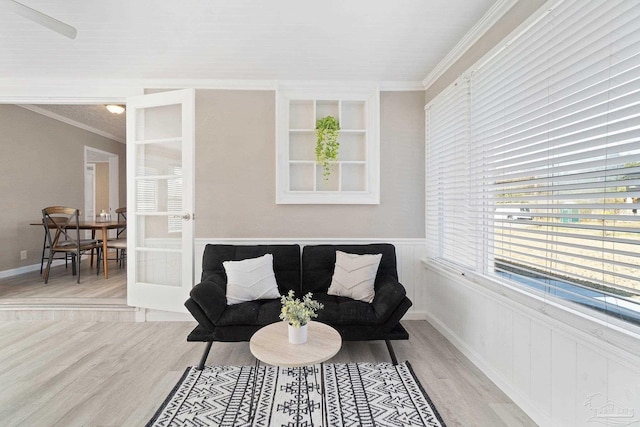 sitting room featuring french doors, light hardwood / wood-style floors, crown molding, and built in shelves