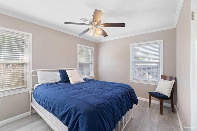 bedroom with light hardwood / wood-style flooring, ceiling fan, crown molding, and multiple windows