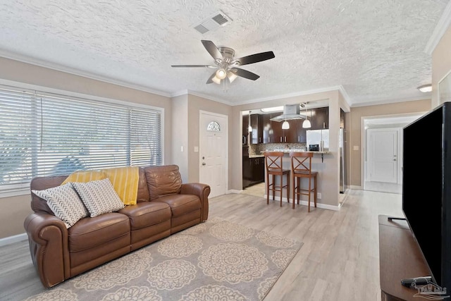 living room with light hardwood / wood-style floors, ornamental molding, a textured ceiling, and ceiling fan